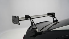 Front close-up of a black BMW G87 M2 featuring an aggressive carbon fiber front bumper, deep front splitter, large air intakes, and gloss carbon fiber aero details in a studio setting.
