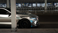 Matte gray BMW G82 M4 featuring an aggressive REVOZPORT carbon fiber aero kit with vented hood, front canards, wide fender vents, and illuminated LED headlights in a nighttime parking garage.