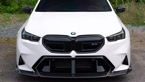 White BMW G90 M5 featuring a REVOZPORT carbon fiber front lip, side skirts, and aggressive front aero styling parked in a natural outdoor setting.