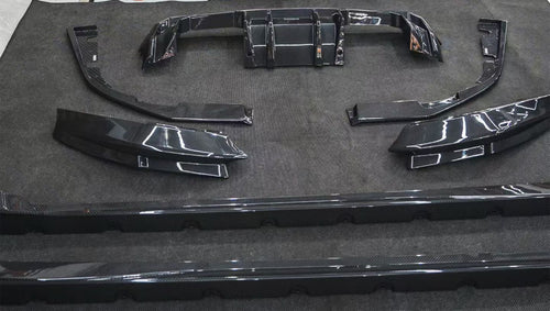 REVOZPORT glossy carbon fiber body kit components displayed before installation, including front lip sections, side skirts, rear diffuser, and aero trim pieces.