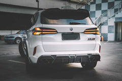 Front view of a white BMW X5M featuring a REVOZPORT carbon fiber front lip and aggressive front bumper aero styling parked on an urban street at night.