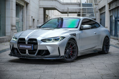 Silver BMW G82 M4 featuring a REVOZPORT carbon fiber body kit with front lip, side skirts, vented fenders, and aggressive aero styling parked in a modern urban courtyard.