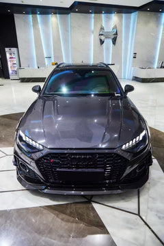 Black Audi RS4 Avant featuring a REVOZPORT carbon fiber body kit with front lip, side skirts, and aggressive aero styling displayed inside a luxury showroom.