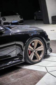 Black Audi RS4 Avant featuring a REVOZPORT carbon fiber body kit with front lip, side skirts, and aggressive aero styling displayed inside a luxury showroom.