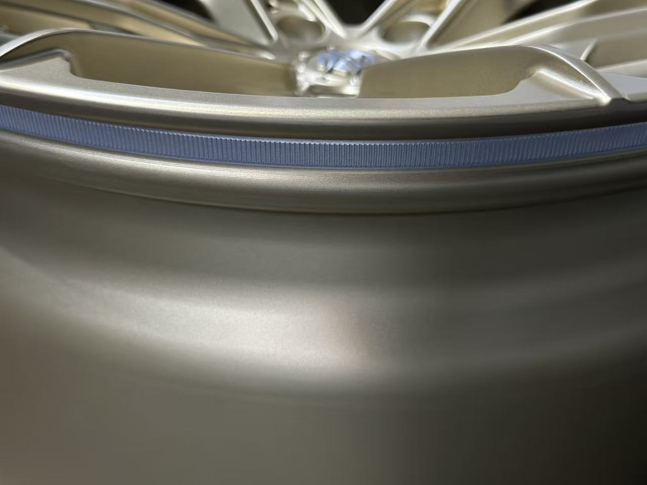 Bronze REVOZPORT forged alloy wheel with split multi-spoke design displayed on a black textured workshop floor.