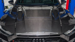 Black Audi RS7 featuring a REVOZPORT carbon fiber body kit with front lip, side skirts, carbon hood, and aggressive aero styling driving on a city street.