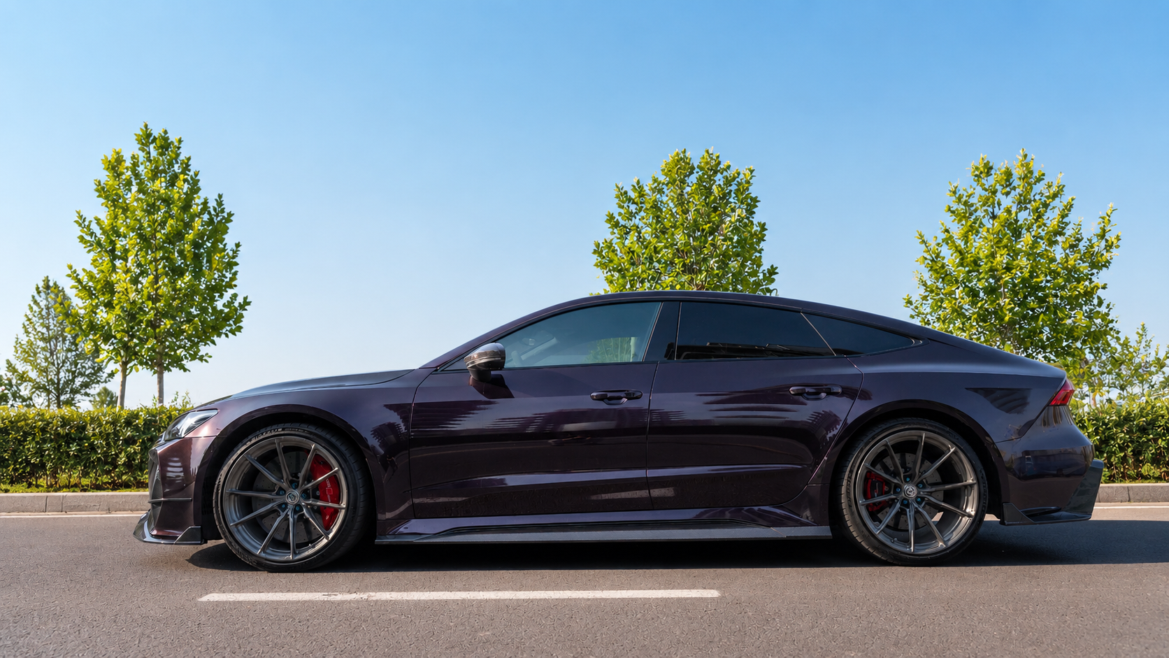 Black Audi RS7 featuring a REVOZPORT carbon fiber body kit with front lip, side skirts, carbon hood, and aggressive aero styling driving on a city street.