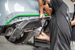 Hands-on carbon fiber diffuser installation highlighting precision fitment, detailed craftsmanship, and motorsport-inspired aero components inside a professional workshop environment.