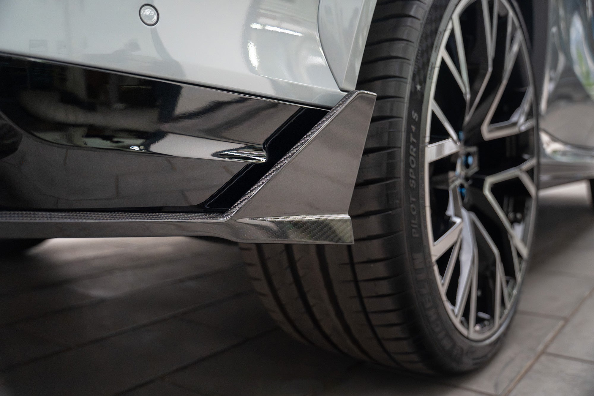 Hands-on carbon fiber diffuser installation highlighting precision fitment, detailed craftsmanship, and motorsport-inspired aero components inside a professional workshop environment.