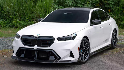 White BMW G90 M5 featuring a REVOZPORT carbon fiber front lip, side skirts, and aggressive front aero styling parked in a natural outdoor setting.