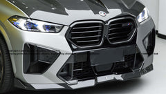 Gray BMW X5M featuring a REVOZPORT carbon fiber body kit with aggressive front lip, enlarged air intakes, side skirts, and sporty aero styling displayed inside a performance workshop.