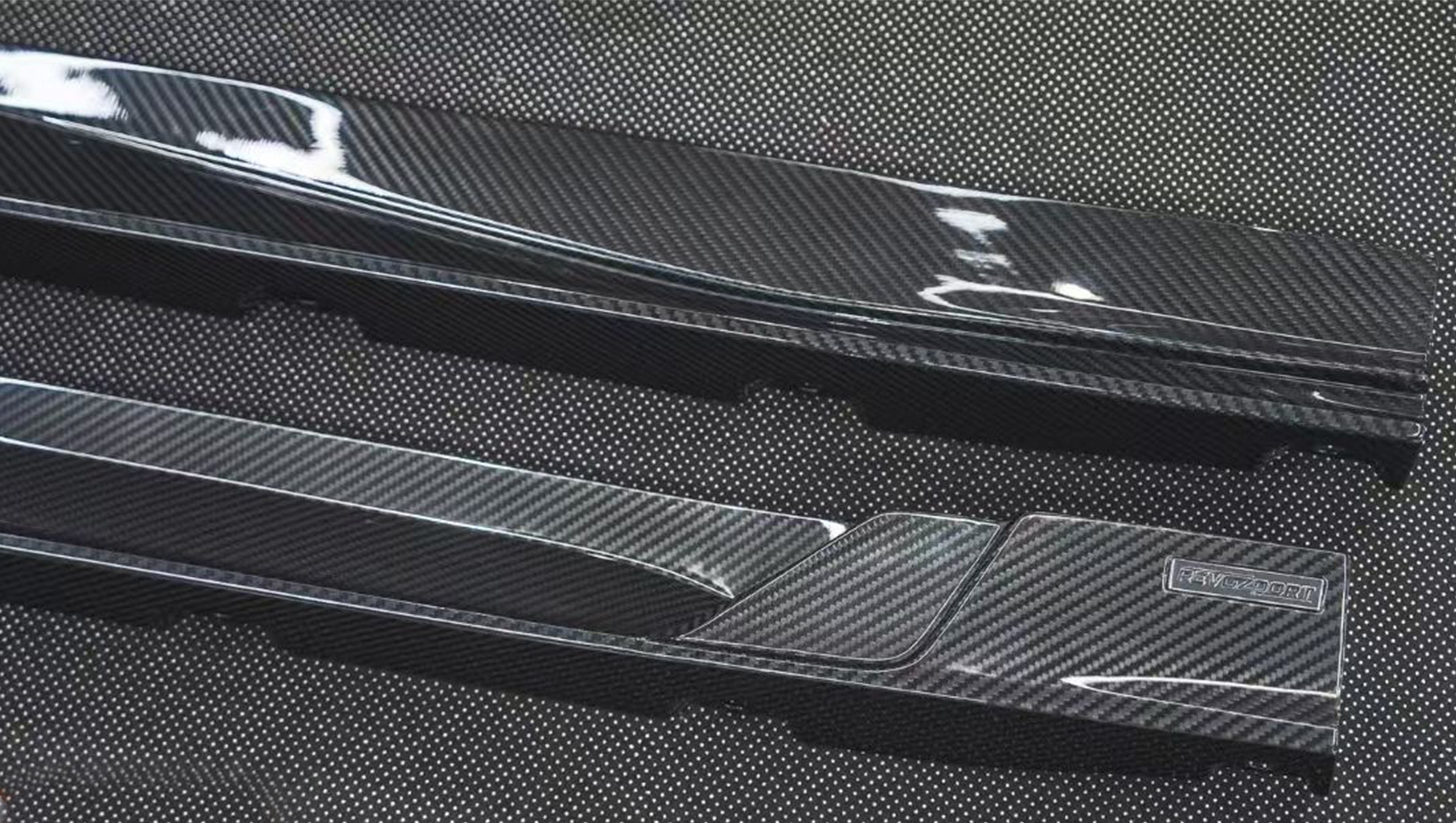 REVOZPORT glossy carbon fiber body kit components displayed before installation, including front lip sections, side skirts, rear diffuser, and aero trim pieces.