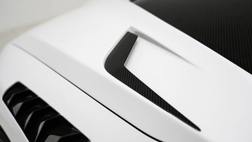 White BMW G80 M3 featuring a REVOZPORT carbon fiber body kit with front lip, side skirts, canards, vented fenders, and yellow DRL headlights displayed in a clean studio setting.
