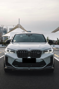 White BMW X4M featuring a REVOZPORT front grille upgrade and sporty front-end styling parked on an open urban road.