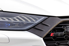 White Audi RS6 Avant featuring a REVOZPORT carbon fiber body kit with front lip, side skirts, rear diffuser, and lowered stance parked in a modern urban waterfront setting.