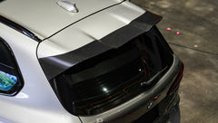 Gray BMW X5M featuring a REVOZPORT carbon fiber body kit with aggressive front lip, enlarged air intakes, side skirts, and sporty aero styling displayed inside a performance workshop.