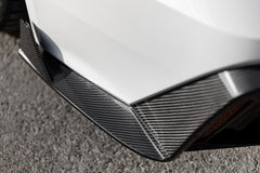 White Audi RS6 Avant featuring a REVOZPORT carbon fiber body kit with front lip, side skirts, rear diffuser, and lowered stance parked in a modern urban waterfront setting.