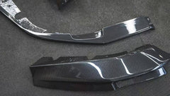 REVOZPORT glossy carbon fiber body kit components displayed before installation, including front lip sections, side skirts, rear diffuser, and aero trim pieces.
