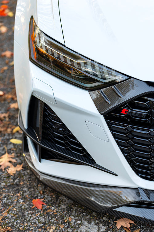 White Audi RS6 Avant featuring a REVOZPORT carbon fiber body kit with front lip, side skirts, rear diffuser, and lowered stance driving at high speed on a highway.