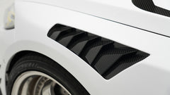 White BMW G80 M3 featuring a REVOZPORT carbon fiber body kit with front lip, side skirts, canards, vented fenders, and yellow DRL headlights displayed in a clean studio setting.