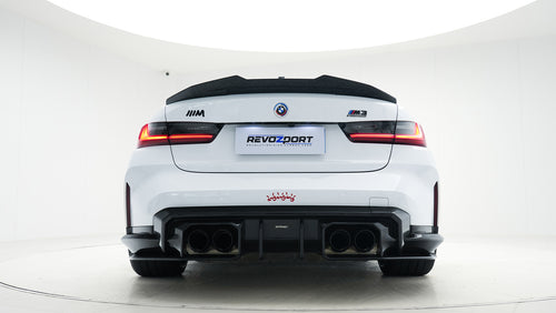 White BMW G80 M3 featuring a REVOZPORT carbon fiber body kit with front lip, side skirts, canards, vented fenders, and yellow DRL headlights displayed in a clean studio setting.