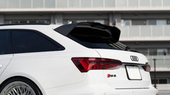 White Audi RS6 Avant featuring a REVOZPORT carbon fiber body kit with front lip, side skirts, rear diffuser, and lowered stance driving at high speed on a highway.