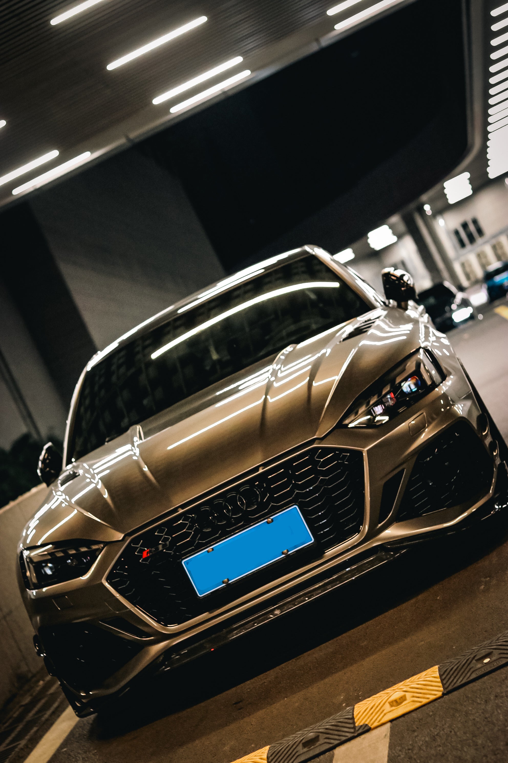 Top-down view of a gray Audi RS5 Sportback featuring a REVOZPORT carbon fiber body kit with vented hood, front lip, side skirts, and large rear wing driving through a dimly lit urban tunnel at night.