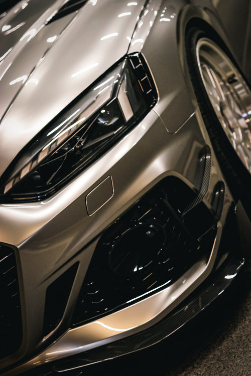 Top-down view of a gray Audi RS5 Sportback featuring a REVOZPORT carbon fiber body kit with vented hood, front lip, side skirts, and large rear wing driving through a dimly lit urban tunnel at night.