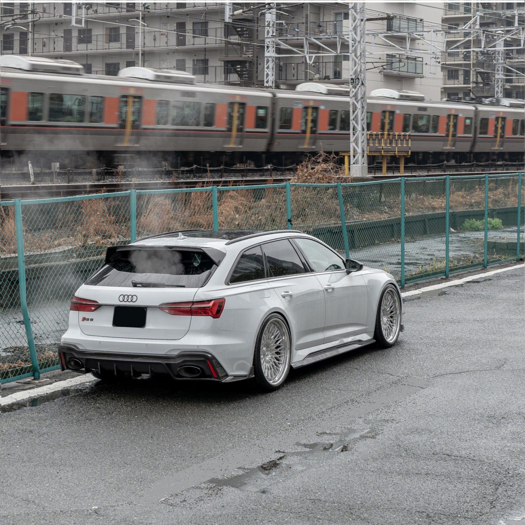 White Audi RS6 Avant featuring a REVOZPORT carbon fiber body kit with front lip, side skirts, rear diffuser, and lowered stance driving at high speed on a highway.