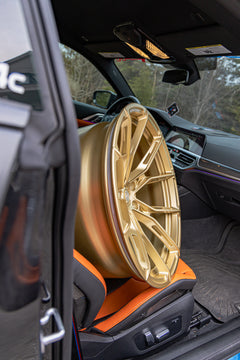 Interior detail of a BMW featuring bronze forged wheel fitment, carbon fiber cabin accents, and stripped track-focused atmosphere.