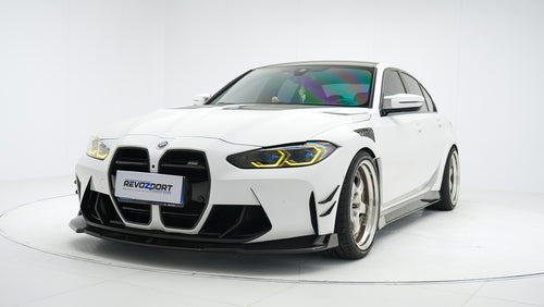 White BMW G80 M3 featuring a REVOZPORT carbon fiber body kit with front lip, side skirts, canards, vented fenders, and yellow DRL headlights displayed in a clean studio setting.