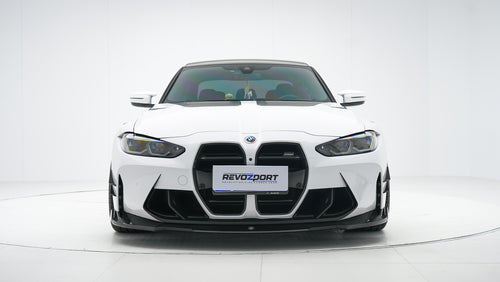 White BMW G80 M3 featuring a REVOZPORT carbon fiber body kit with front lip, side skirts, canards, vented fenders, and yellow DRL headlights displayed in a clean studio setting.