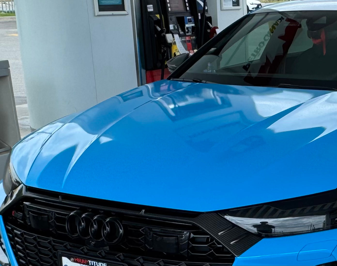 Blue Audi RS7 fitted with a REVOZPORT carbon fiber front lip and aggressive front aero styling, parked in an outdoor parking lot.